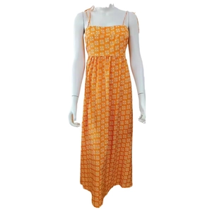 Detail of orange floral maxi dress featuring thin spaghetti straps and pleated high waist