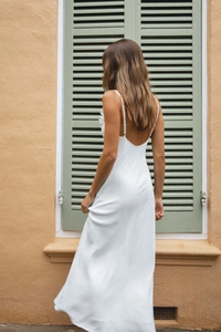 Detail of white backless summer dress featuring delicate thin straps and silky draped fabric