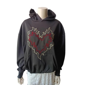 Detailed close-up of intricate heart-shaped flame embroidery on a black hoodie