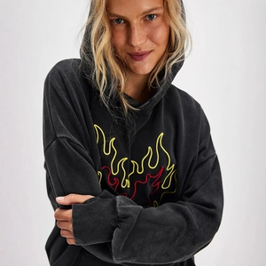 Close-up of vibrant red and yellow flame embroidery on a charcoal oversized hoodie
