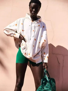 Oversized white hoodie with orange floral print and casual green shorts for autumn wear