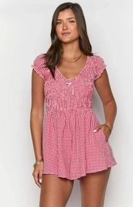 Detail of red gingham mini dress featuring smocked bodice and V-neck with bow accent