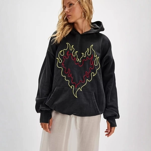 Detailed close-up of a vintage black hoodie featuring flame heart embroidery and kangaroo pocket