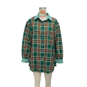 Détail de la chemise à carreaux verts montrant des motifs contrastés sur le col et les poignets