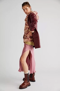 Detail of burgundy leather coat layered with a geometric pattern hoodie and satin skirt