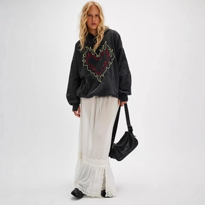 Detail of floral lace trim on white midi skirt paired with black embroidered hoodie
