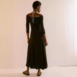 Back detail of an off-shoulder black dress with white halter ties and slim fit design