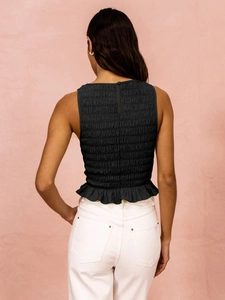 Detail of black smocked sleeveless top featuring ruffle hem and back button closure