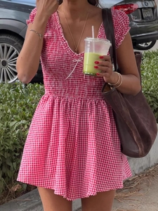 Close-up of red gingham romper featuring smocked waist and delicate bow detail