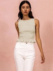 Detail view of beige smocked sleeveless top with peplum hem and elastic pleated texture