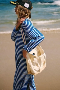 Detail view of a striped long sleeve dress with a white canvas tote bag at the beach