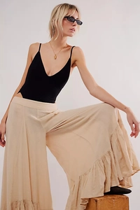 Detail of layered ruffle design on beige wide-leg trousers with soft fabric drape