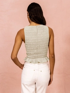Detail of light green smocked sleeveless top with ruffled hem and back button closure
