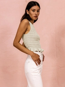 Detail of smocked texture and ruffled hem on an elegant cream sleeveless slim-fit top