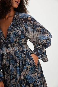 Close-up of V-neck floral print dress featuring elastic smocking and ruffled sleeves