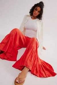 Macro detail of ruffled hem on orange high-waisted wide-leg bohemian trousers