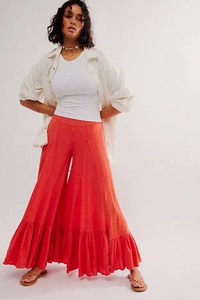Detail of coral red bohemian wide-leg trousers with ruffled hem and linen texture
