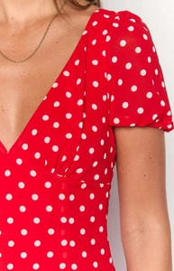 Dettaglio dell'abito rosso a pois con scollo a V ed elegante trama del tessuto a pieghe