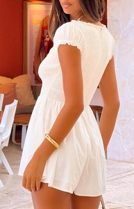 Detail of white smocked romper with puff sleeves and ruffled neckline texture
