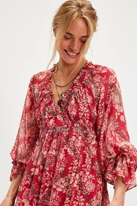 Detail of V-neck with ruffle trim and elastic cuffs on red floral long sleeve dress