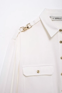 Dettaglio camicia in crêpe bianco con bottoni dorati e spalline decorate eleganti
