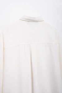 Dettaglio della piega posteriore e dello sprone di una camicia bianca in chiffon