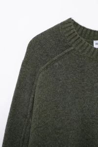 Vue détaillée du col rond et des coutures de manches raglan d'un pull en maille olive foncé