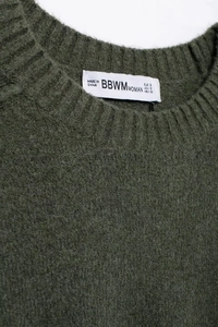 Détail du col d'un pull en maille vert foncé avec bords-côtes et texture douce