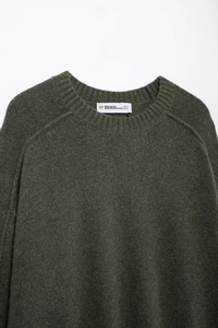 Gros plan d'un pull en maille vert mousse avec col rond côtelé et texture douce en laine