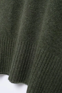 Détail d'un pull en maille vert foncé avec ourlet large côtelé et texture laineuse douce