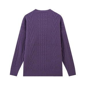 Dettaglio ravvicinato di un maglione viola scuro con motivi a treccia e texture chevron