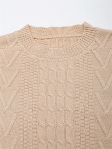 Dettaglio della classica maglia a trecce e della texture su un maglione beige girocollo