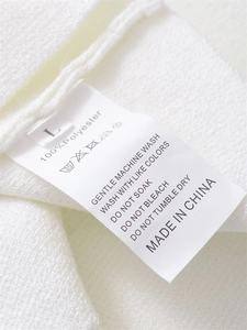 Macro dell'etichetta di cura su gilet bianco in maglia con istruzioni di lavaggio e taglia