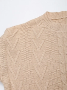 Dettaglio della maglia a trecce e girocollo a costine su maglione invernale beige