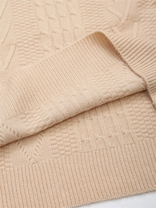 Dettagli della trama a treccia e morbida superficie beige del maglione in maglia