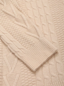 Dettaglio della maglia a trecce e dei polsini a costine sul maglione beige slim fit