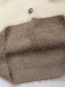 Détail macro du tricot bicolore en peluche avec un bouton vintage argenté gravé