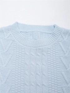 Dettaglio del maglione a trecce azzurro che mostra il girocollo e la trama della lana