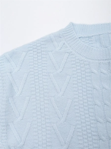Dettaglio maglione in maglia azzurro con trama a trecce e motivo a V in evidenza