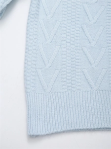 Dettaglio maglione blu chiaro con trama a treccia a V e bordo inferiore a coste spesse