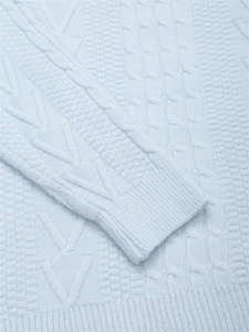 Dettaglio maglione a trecce azzurro con texture intrecciate e polsini a costine