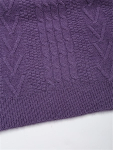 Vista macro della trama a trecce viola scuro e dell'orlo a coste del maglione in maglia