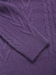 Dettaglio del maglione in maglia viola con trama a treccia e polsini a costine
