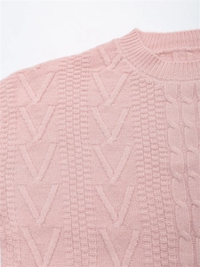 Dettaglio ravvicinato della maglia a trecce rosa con trama a rombi e tessuto morbido al tatto