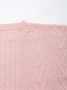 Dettaglio di un maglione rosa a maglia con trecce e scollo rotondo dal design morbido