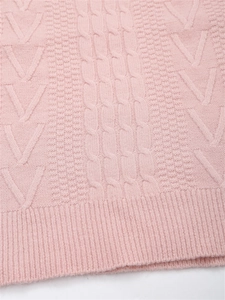 Vista macro dettagliata del maglione a maglia a trecce rosa con orlo a coste e tessuto