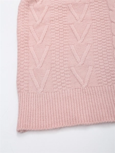 Dettaglio ravvicinato di maglione rosa con trama a treccia a V e bordo inferiore a coste