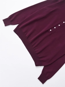 Gros plan détaillé d'un pull en maille violet foncé avec boutons blancs et bords-côtes