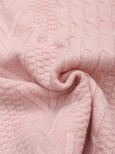 Dettaglio ravvicinato di maglione rosa in maglia con motivi a treccia e trama a rombi