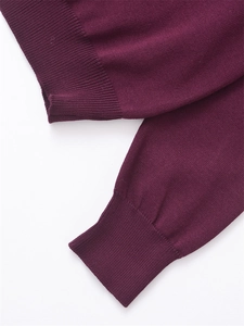 Détail du poignet en maille bordeaux présentant un design classique à côtes